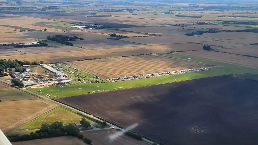 Aerial view of Fenland Airfield during Wings & Wheels 2026, with visiting aircraft on the grass and cars parked the length of the runway