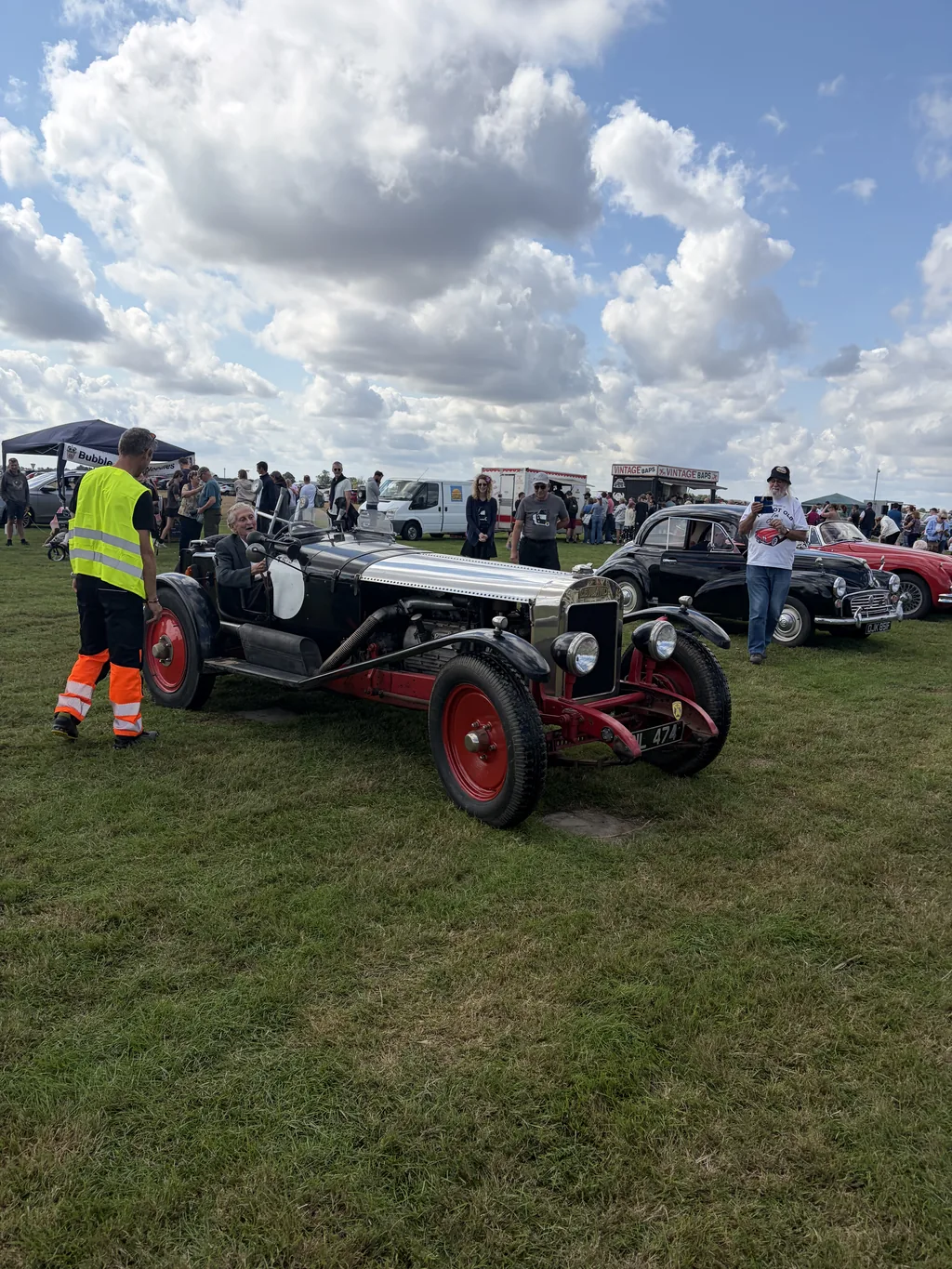 A vintage sports car on the display field with classic cars lined up behind